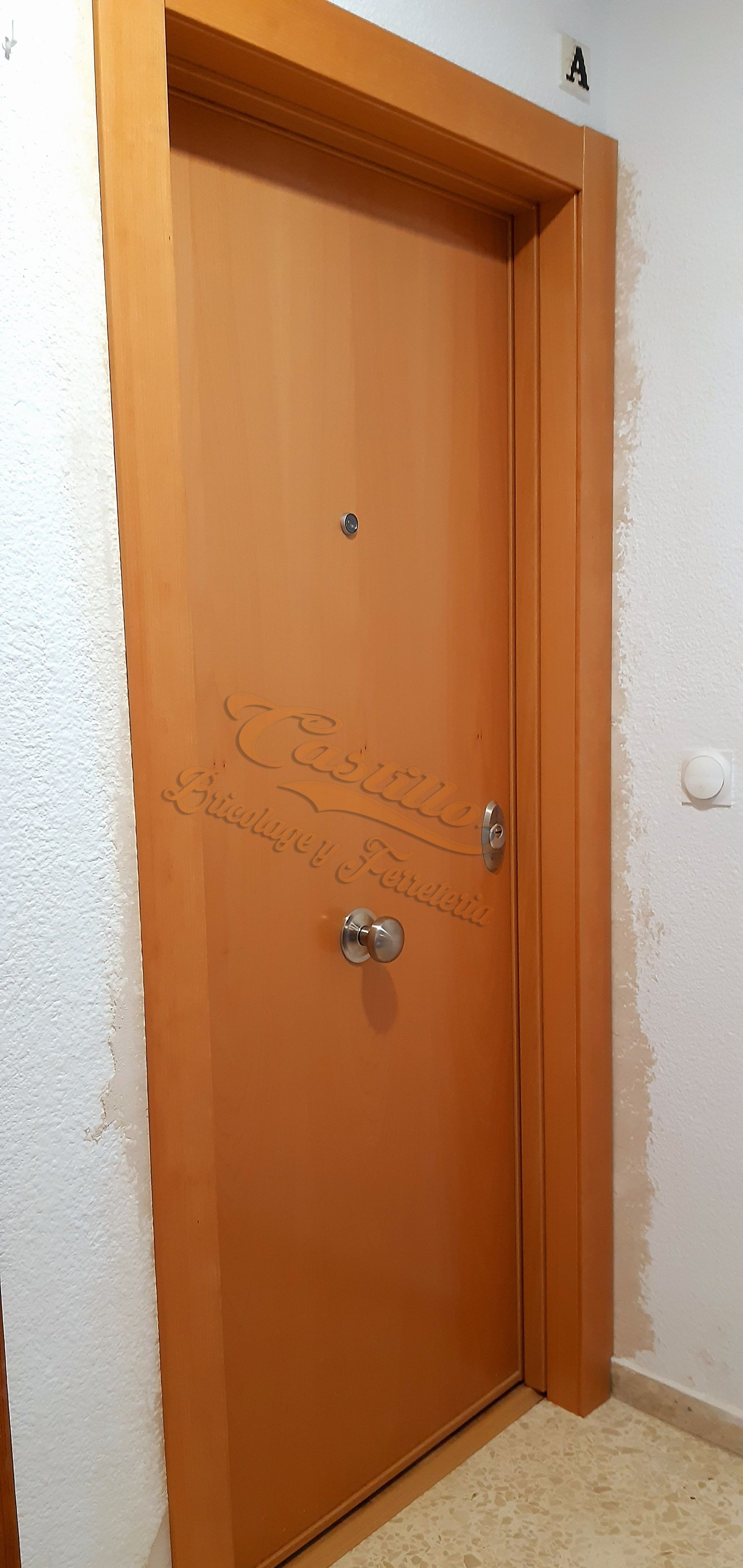 Una puerta de madera está en un pasillo al lado de una escalera.