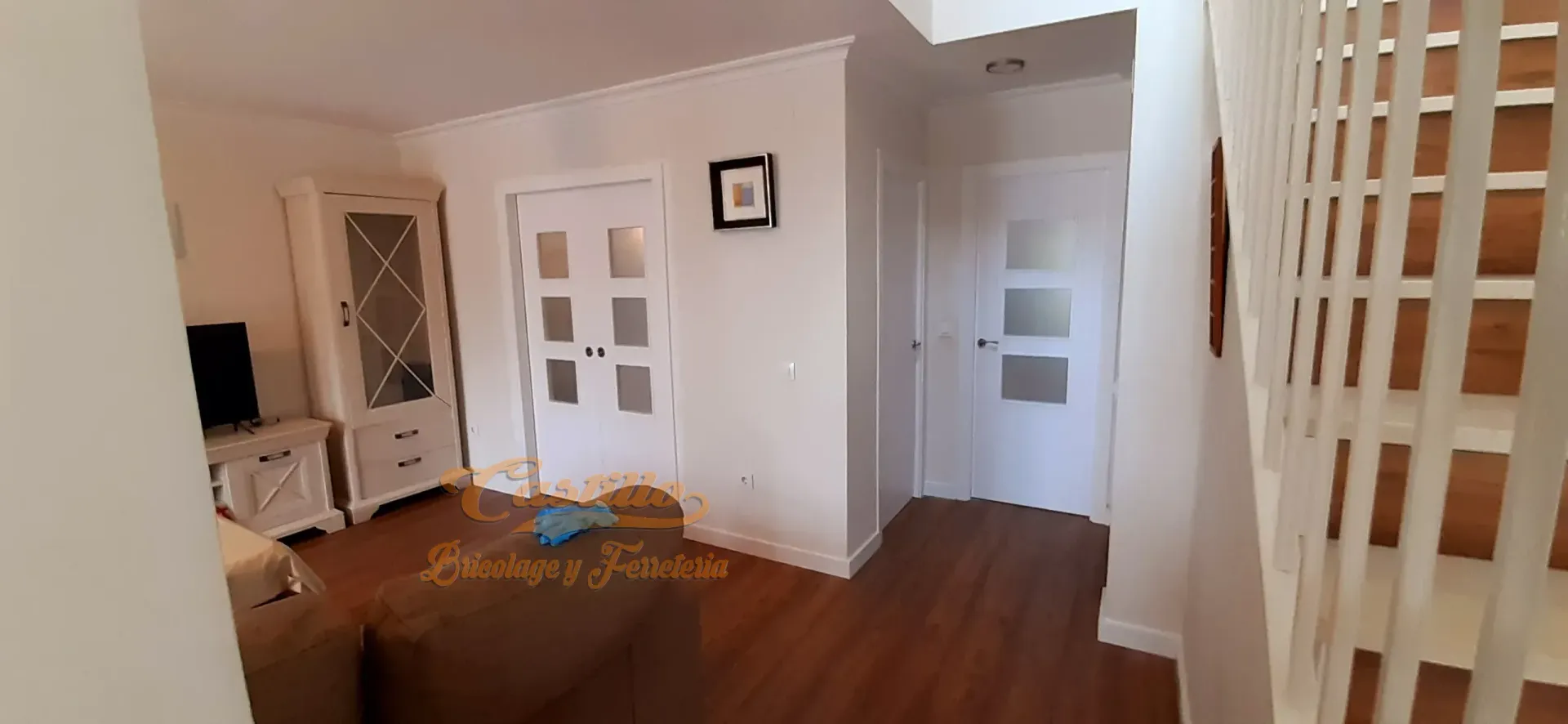 Una sala de estar con pisos de madera y paredes blancas.