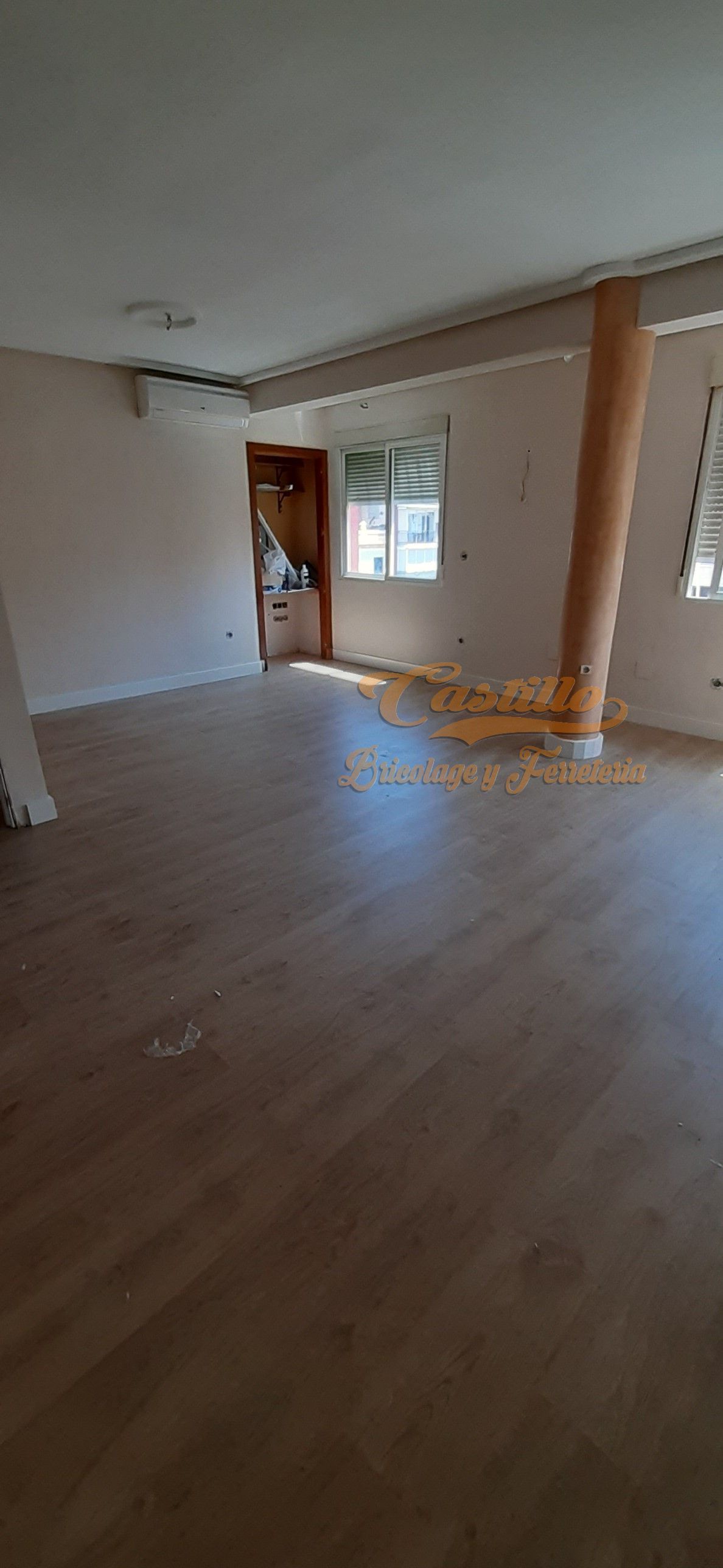 Una gran habitación vacía con suelo de madera y una ventana.