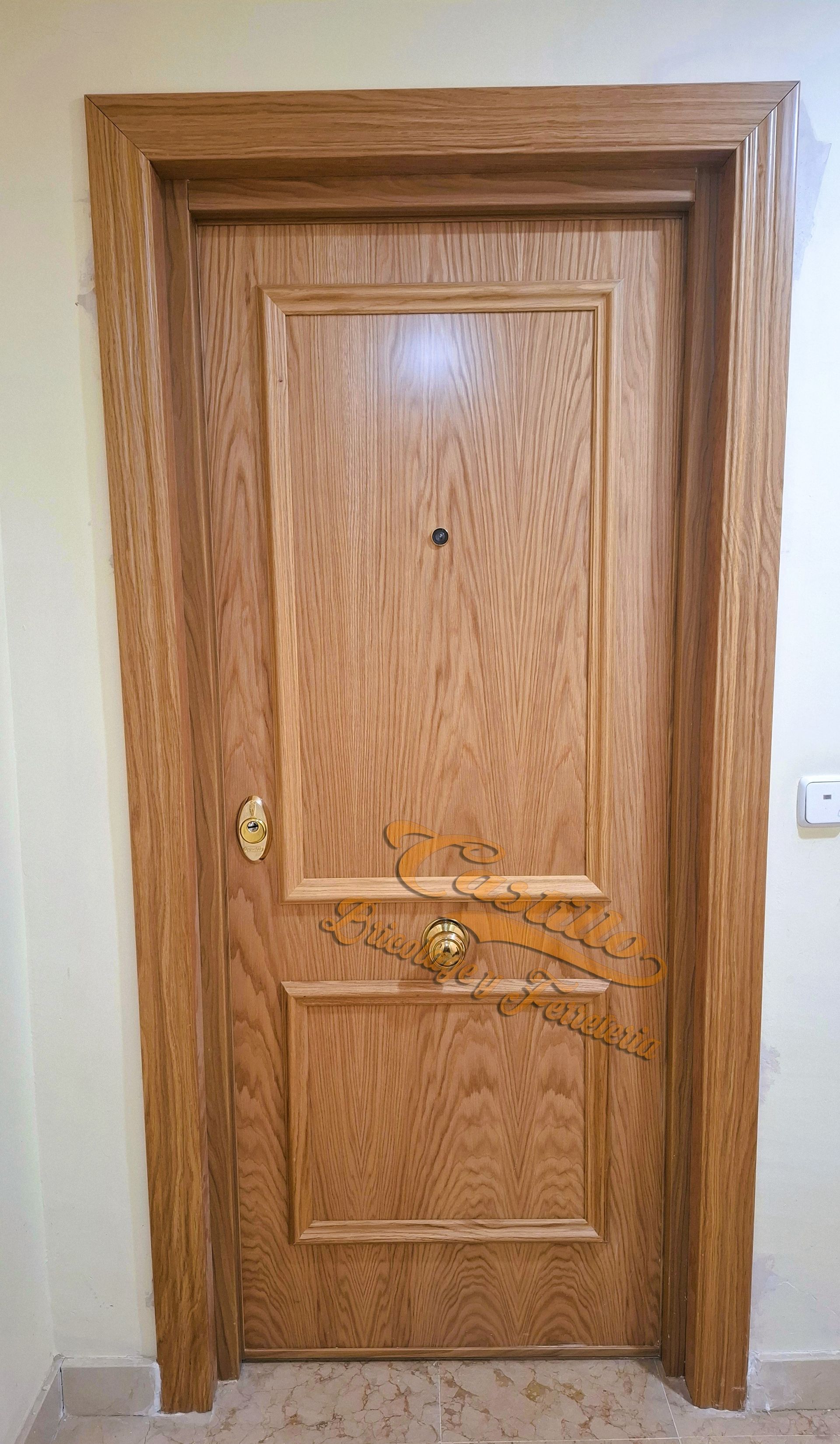 Puerta de madera con panel decorativo. Tirador dorado y mirilla.