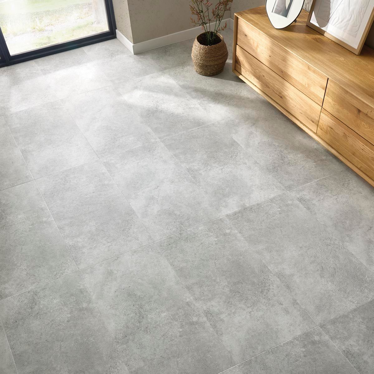 Suelo de baldosas grises con mueble de madera y cesta de mimbre.