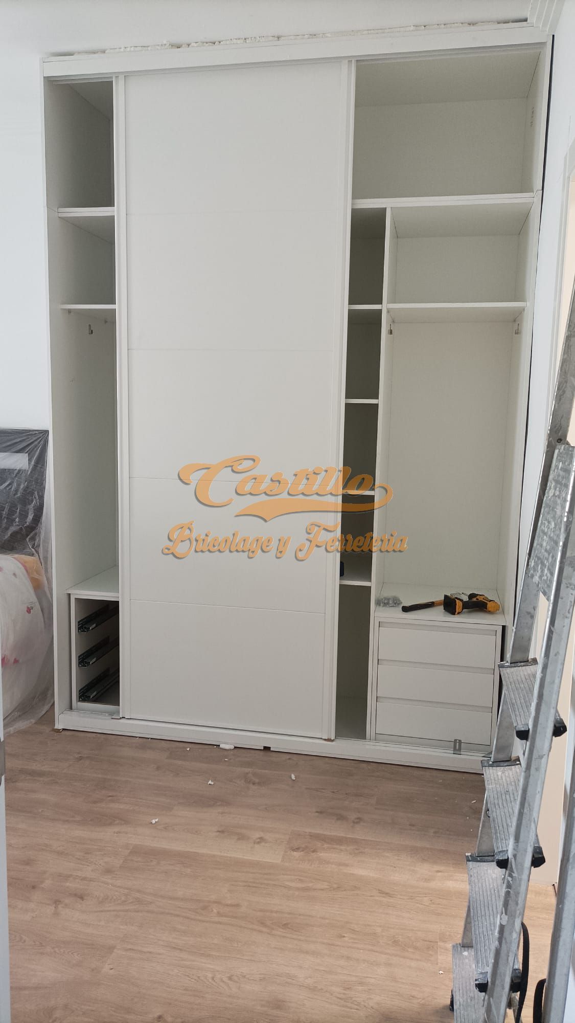 Se está construyendo un armario blanco con puertas correderas en una habitación.