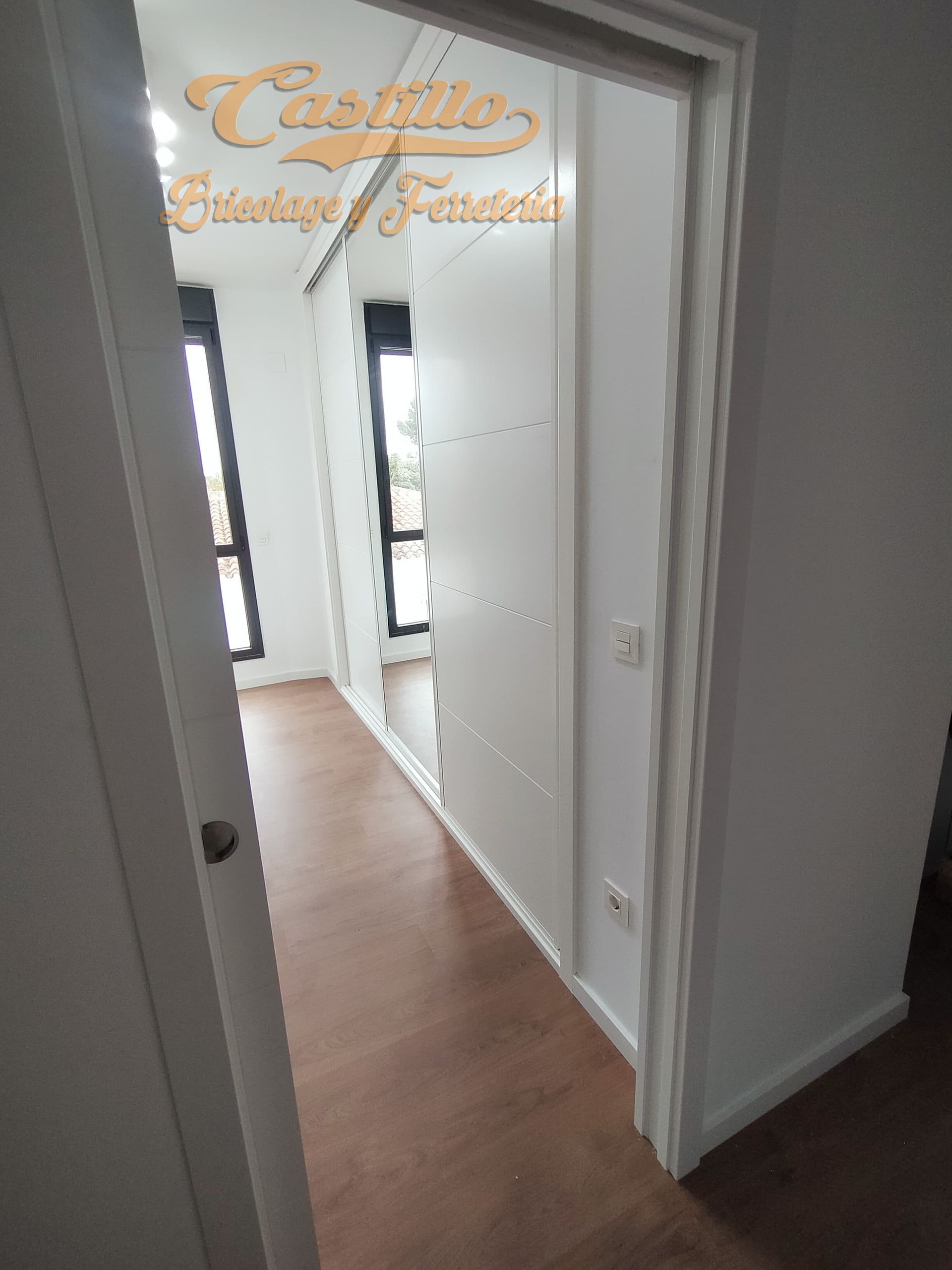 Un pasillo con paredes blancas y pisos de madera en una casa.