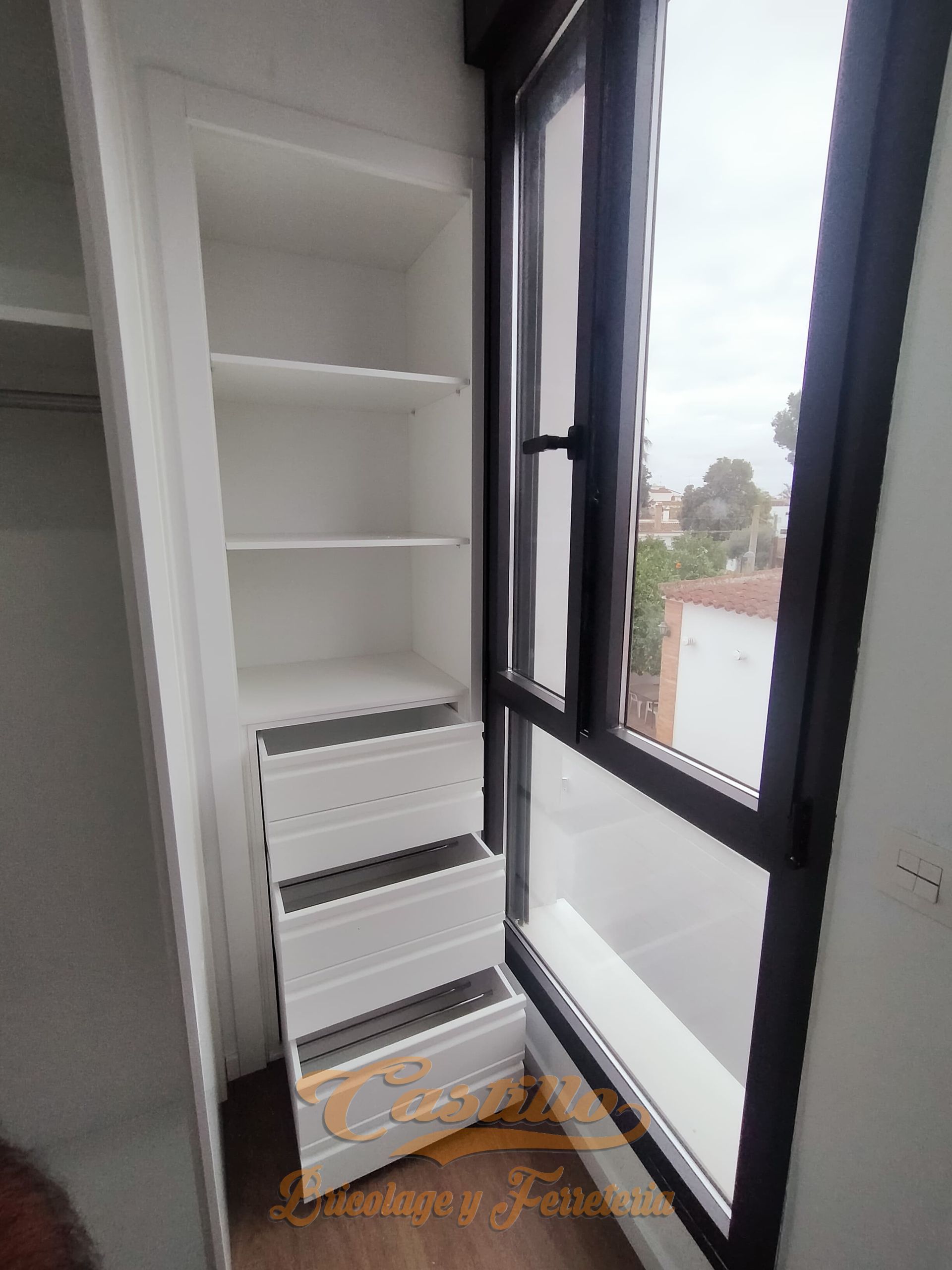 Un armario con estantes y cajones al lado de una ventana.