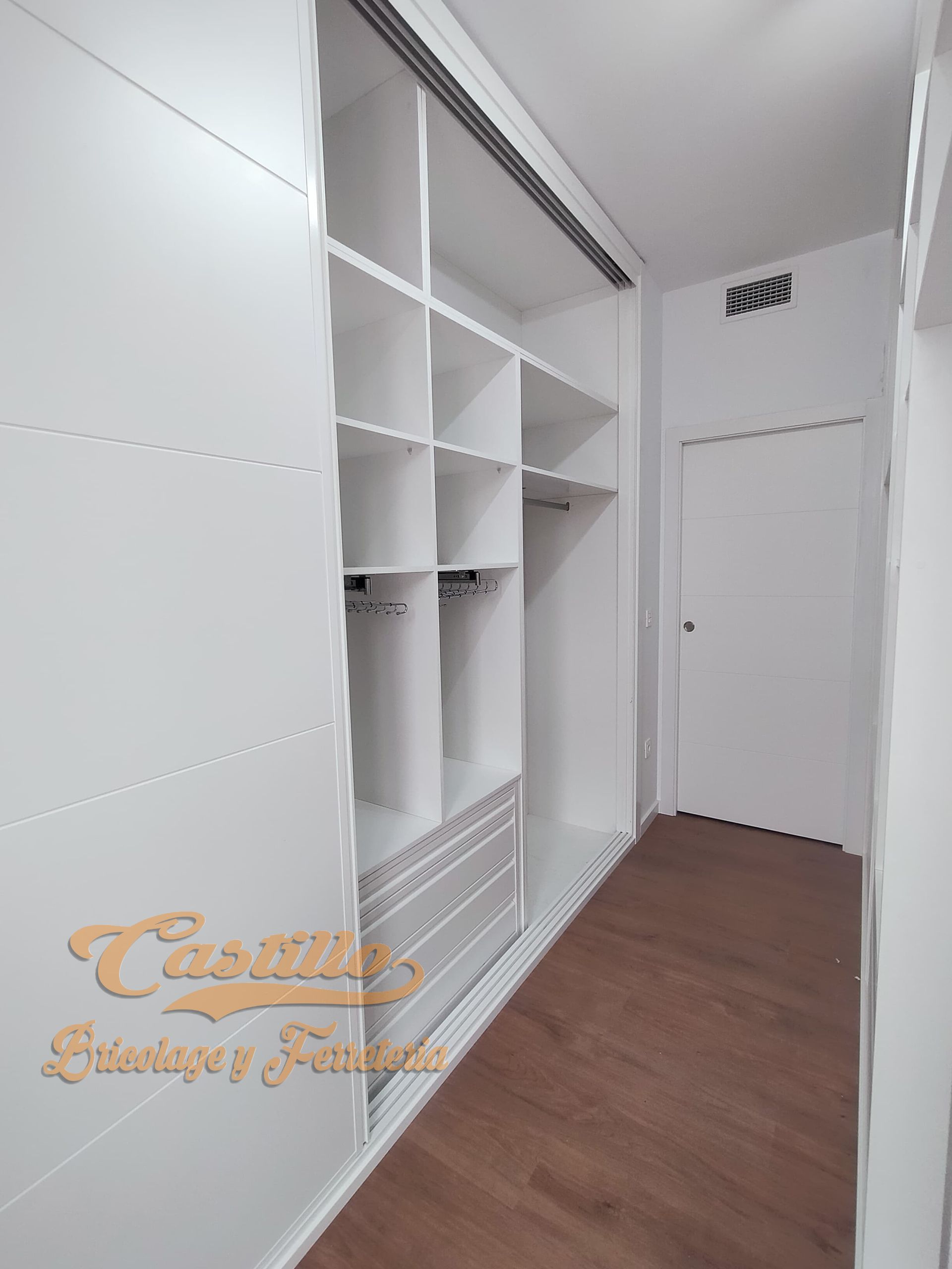 Un vestidor con paredes blancas y pisos de madera.