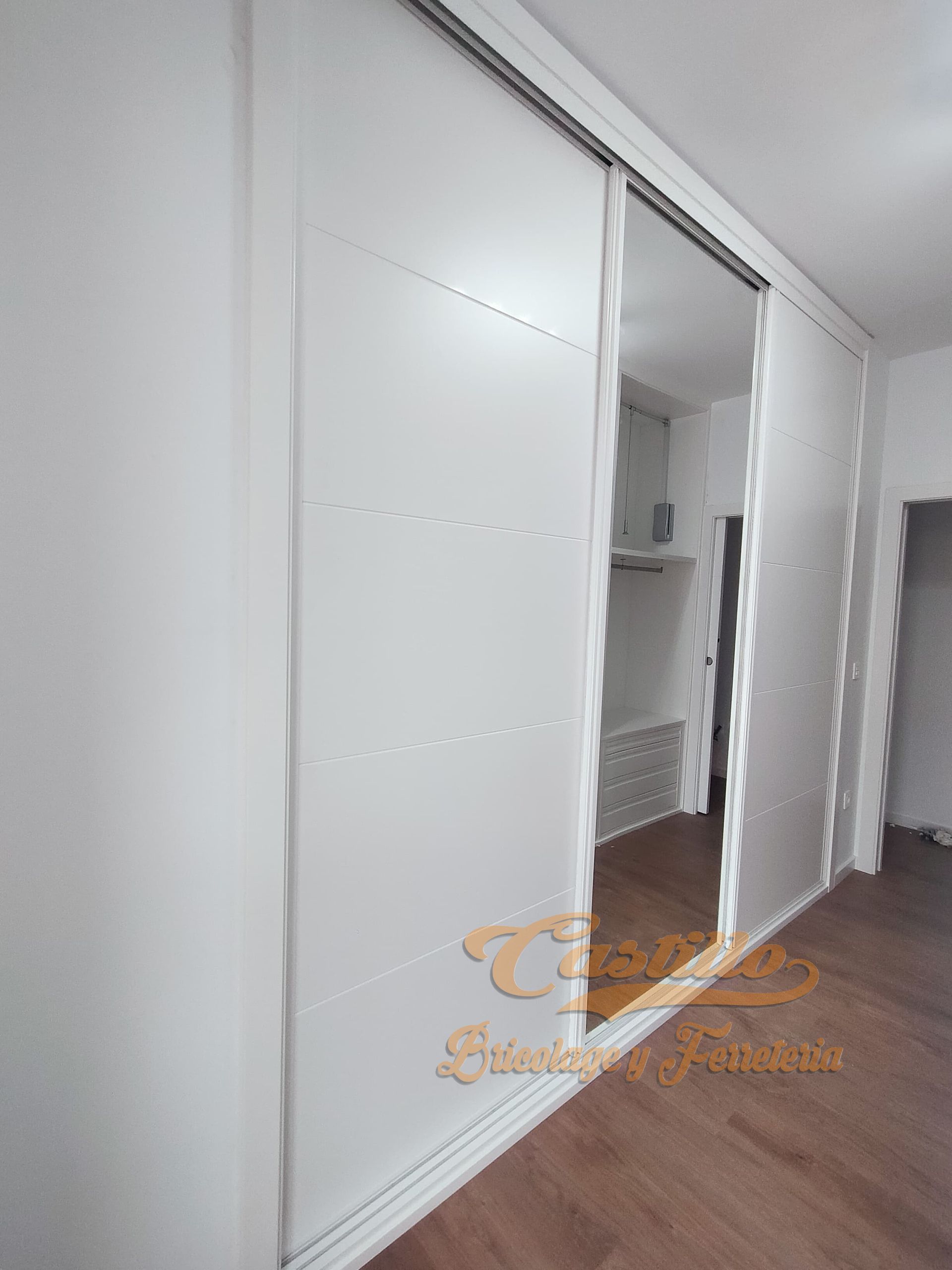 Una pared blanca con puertas corredizas y un espejo.