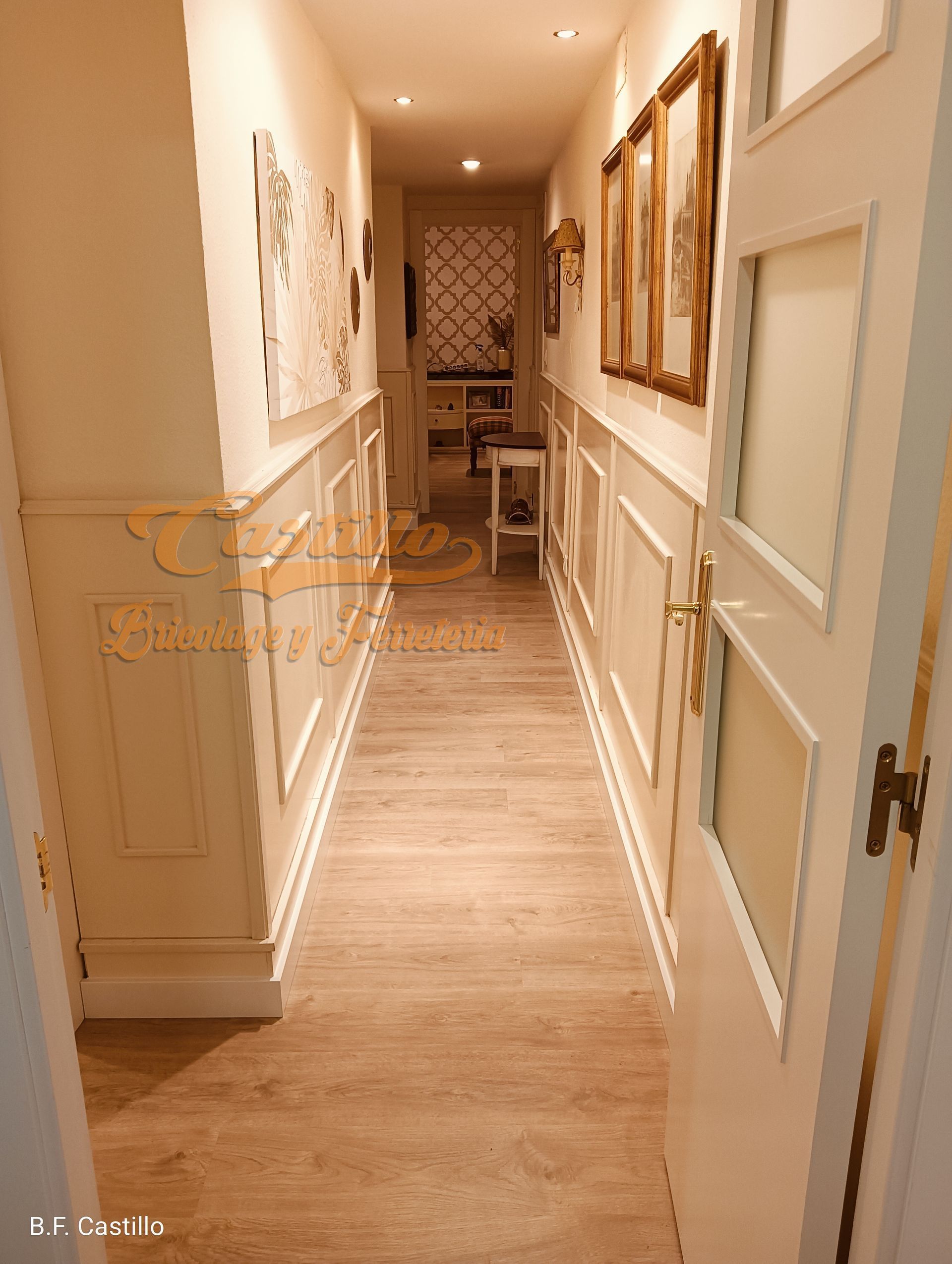 Un largo pasillo con suelos de madera y una puerta blanca.