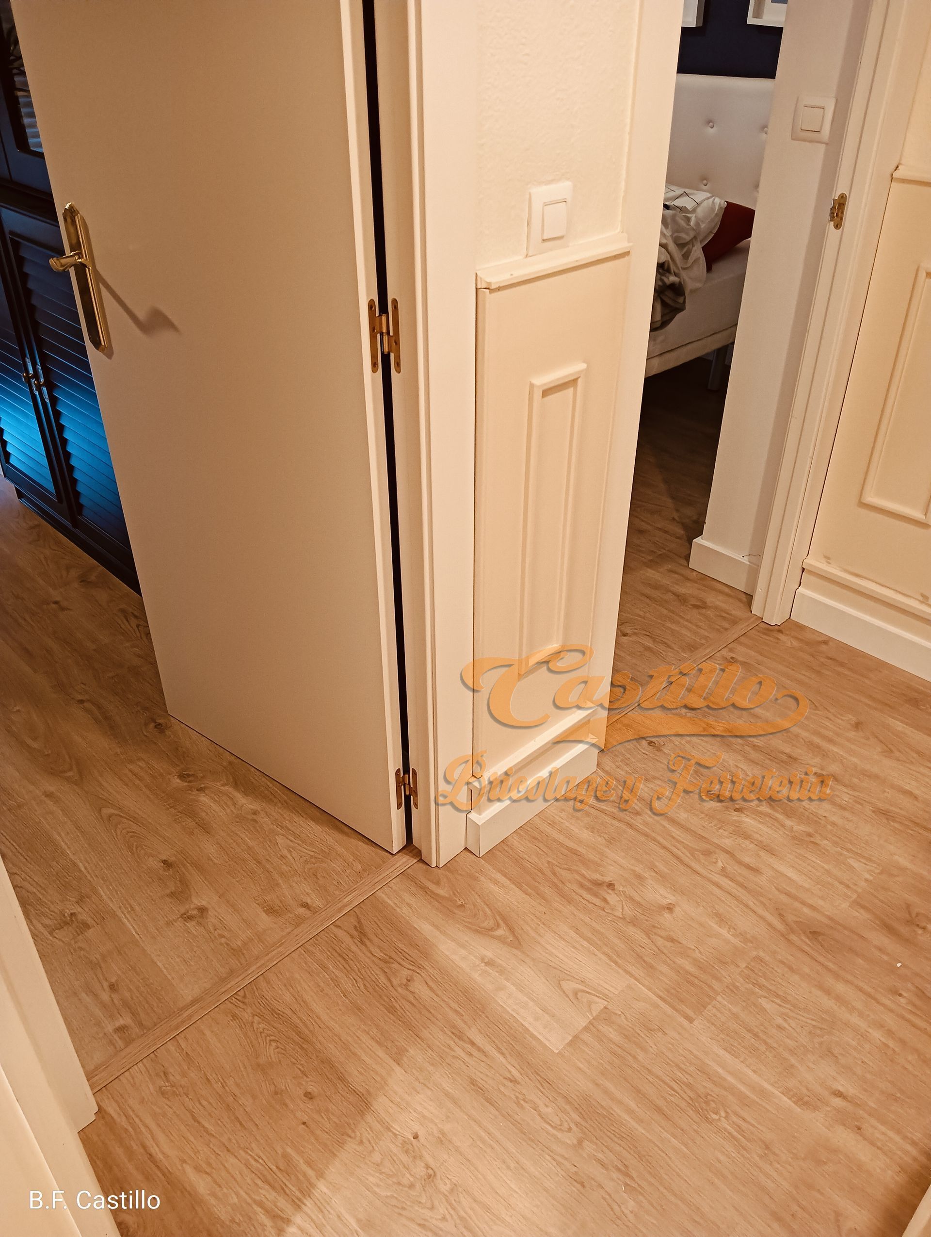 Un pasillo con suelo de madera y una puerta blanca.