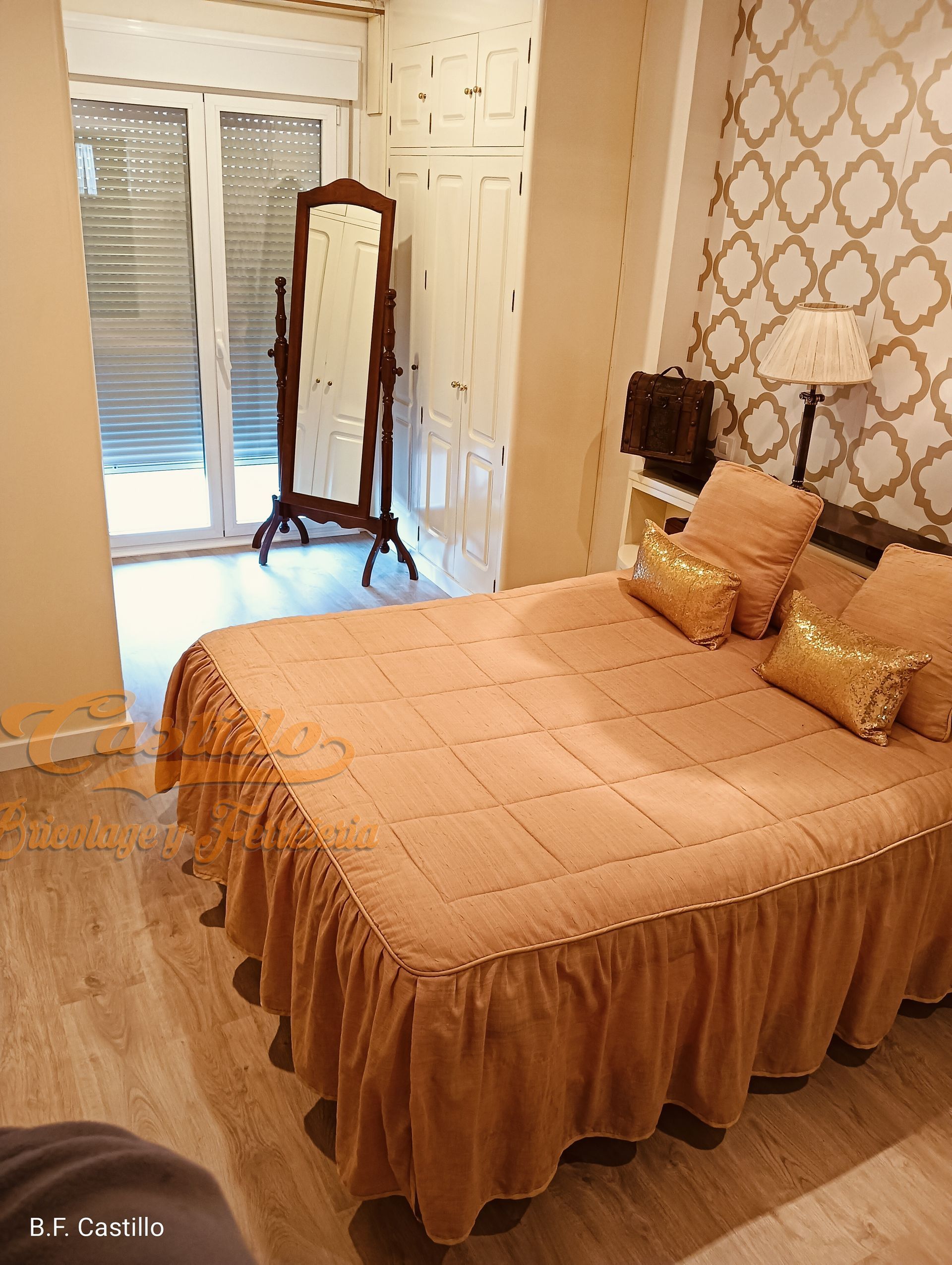 Un dormitorio con cama, espejo y lámpara.