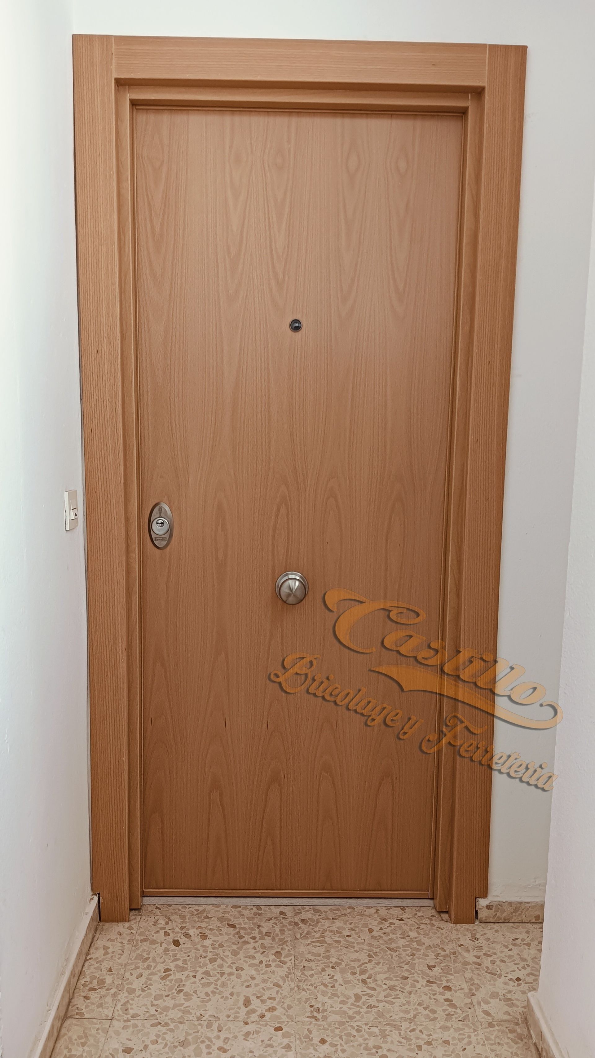 Una puerta de madera está en un pasillo al lado de una pared blanca.