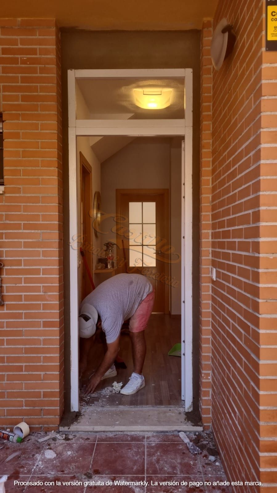 Un hombre está trabajando en una puerta en un edificio de ladrillos.