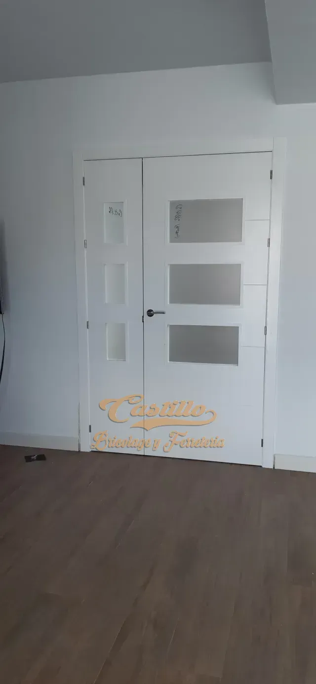 Una habitación vacía con una puerta blanca y un piso de madera.