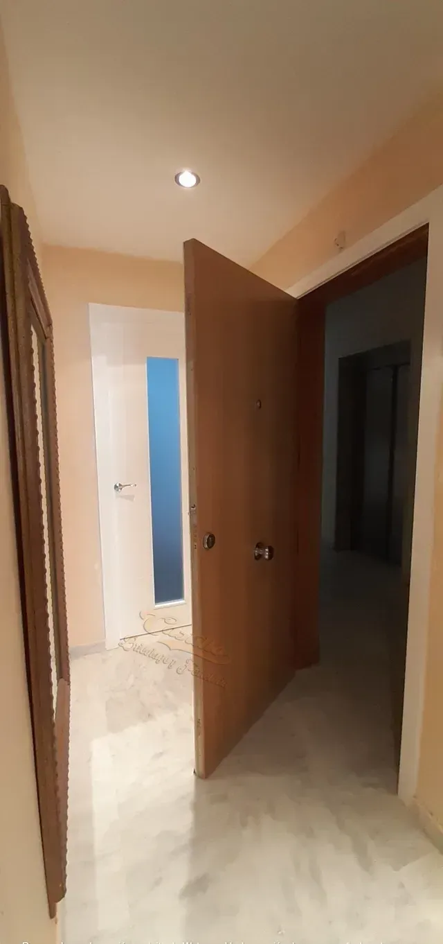 Un pasillo con una puerta de madera y un espejo.