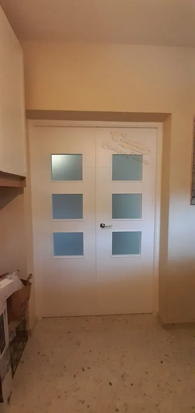 Un par de puertas blancas con vidrio esmerilado en una habitación.