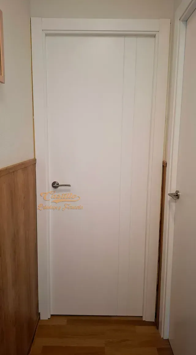 Una puerta blanca está en un pasillo al lado de una pared de madera.