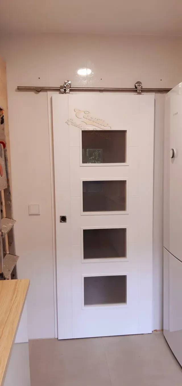 Una puerta de granero corrediza blanca con cuatro ventanas en una cocina.