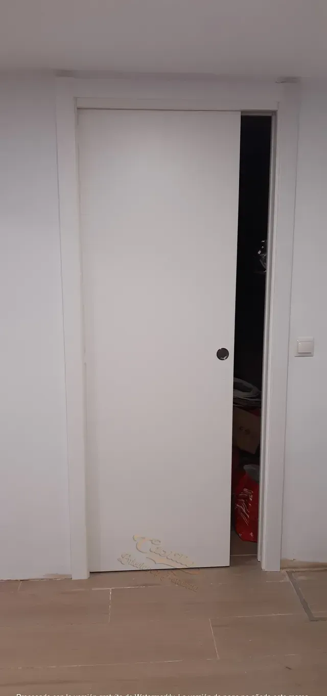 Una puerta corrediza blanca se abre a una habitación oscura.
