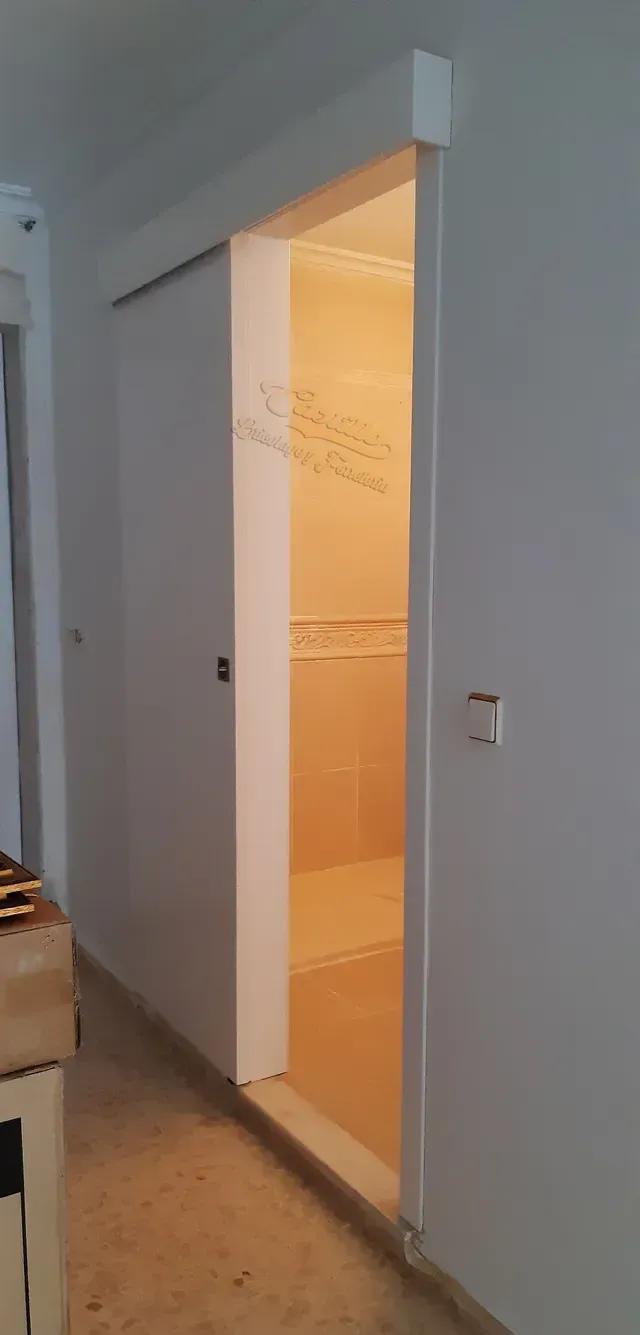Una puerta corrediza en un pasillo que conduce a un baño.