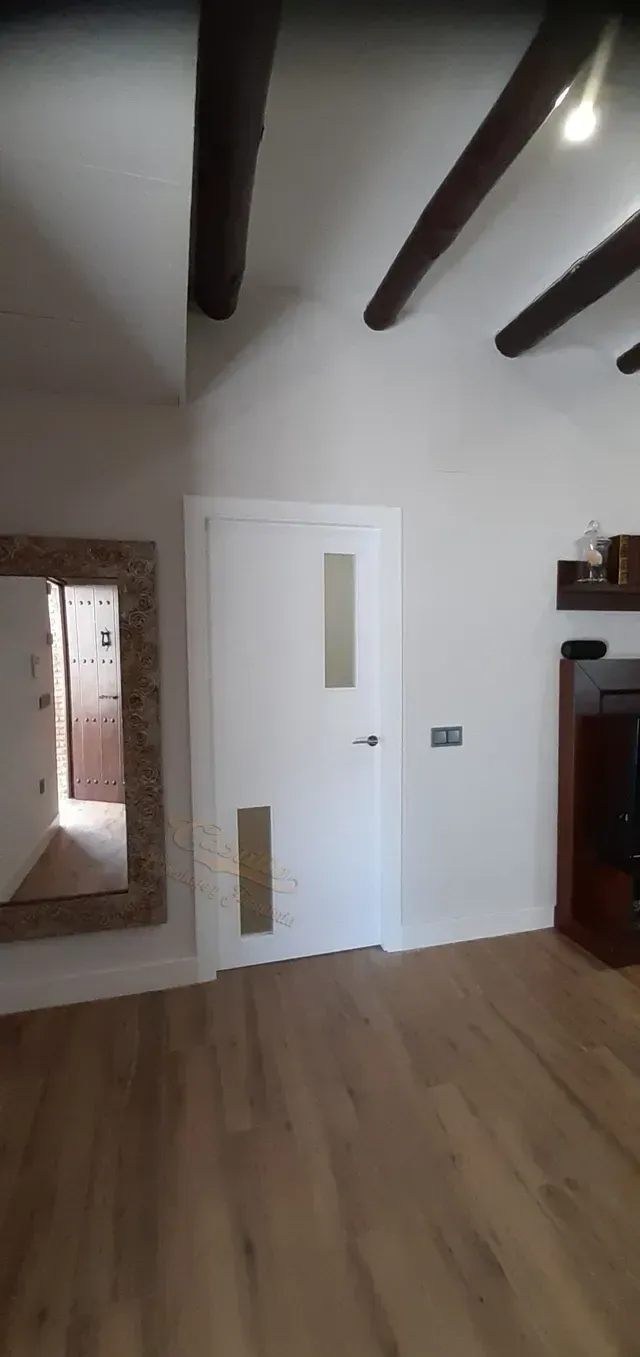 Una sala de estar con una puerta blanca y un espejo.