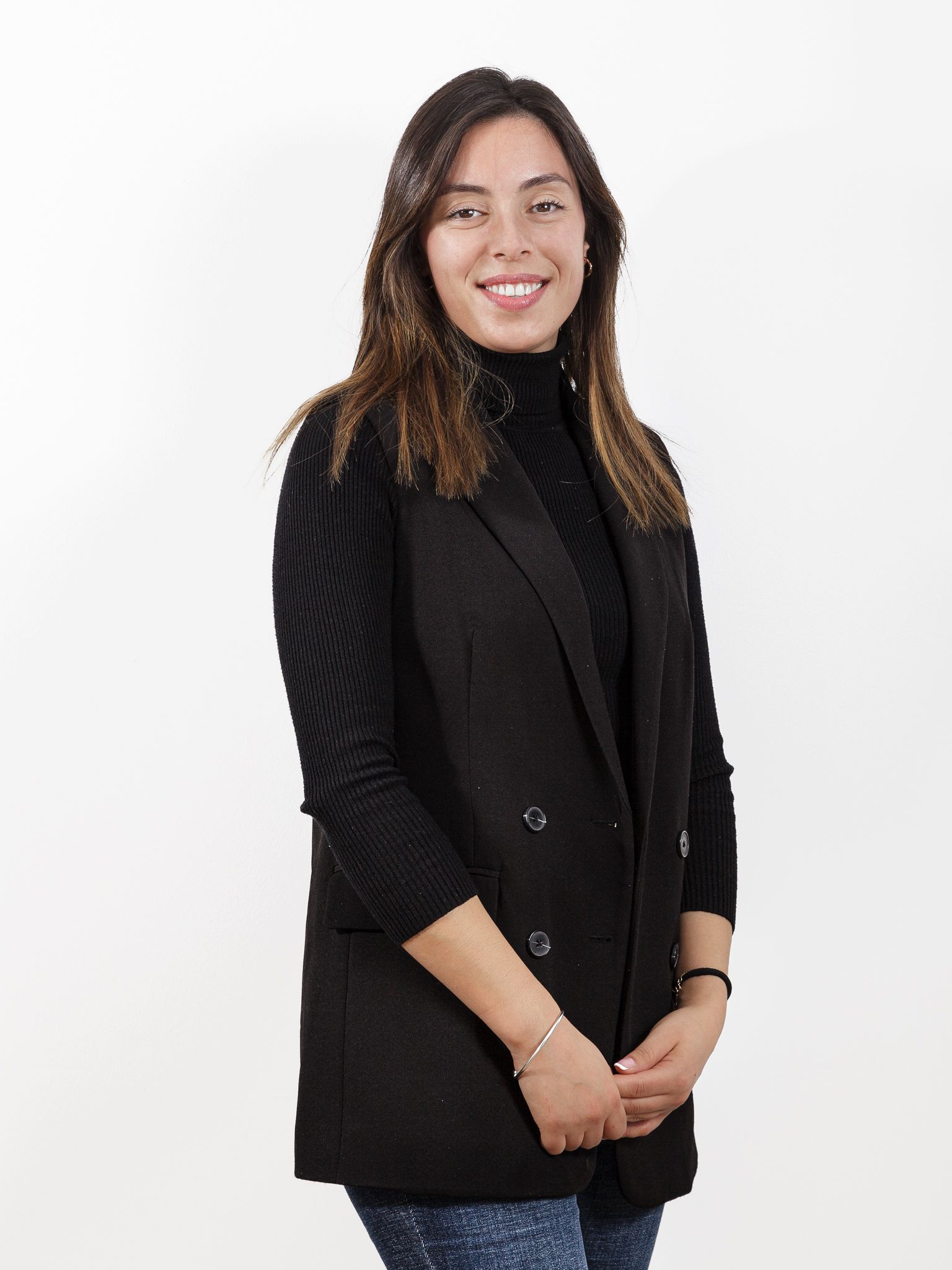 Una mujer lleva un chaleco negro y un cuello alto negro.