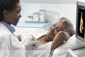 Médico realizando ultrassom de mama em uma paciente idosa sorridente em um ambiente médico.