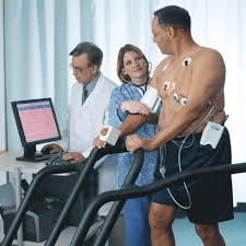 Homem em esteira monitorado por equipe médica, passando por um teste de esforço.