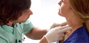Um médico examina o pescoço de um paciente com as mãos enluvadas.