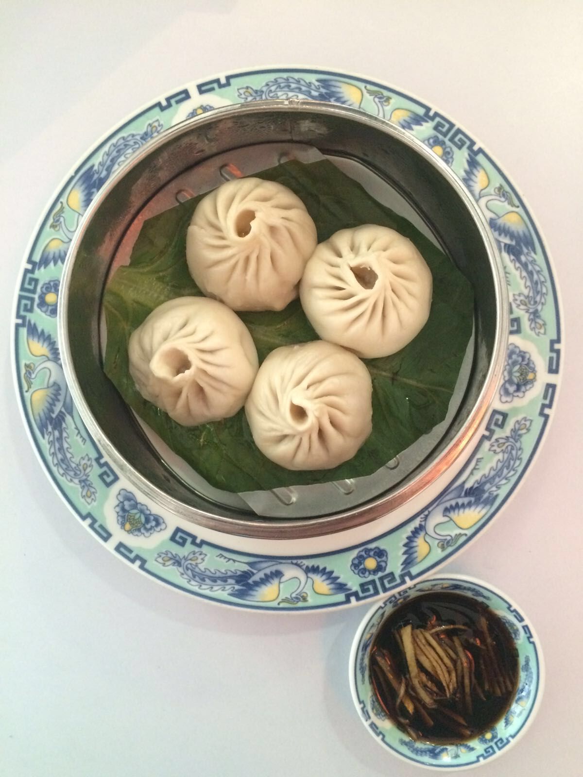 Vier Knödel liegen auf einem Teller neben einer Schüssel mit Dip-Sauce.