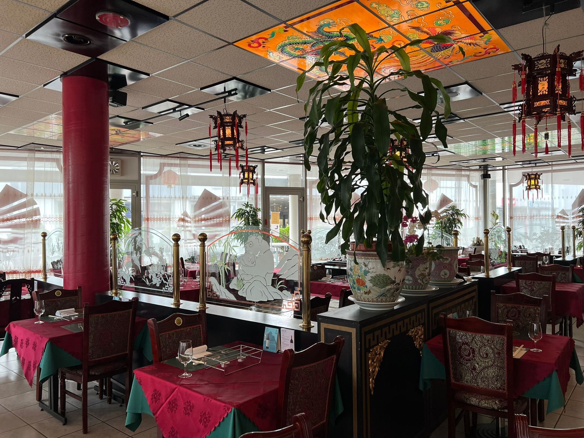 Ein großes Esszimmer mit Tischen und Stühlen und einer Pflanze in der Mitte.