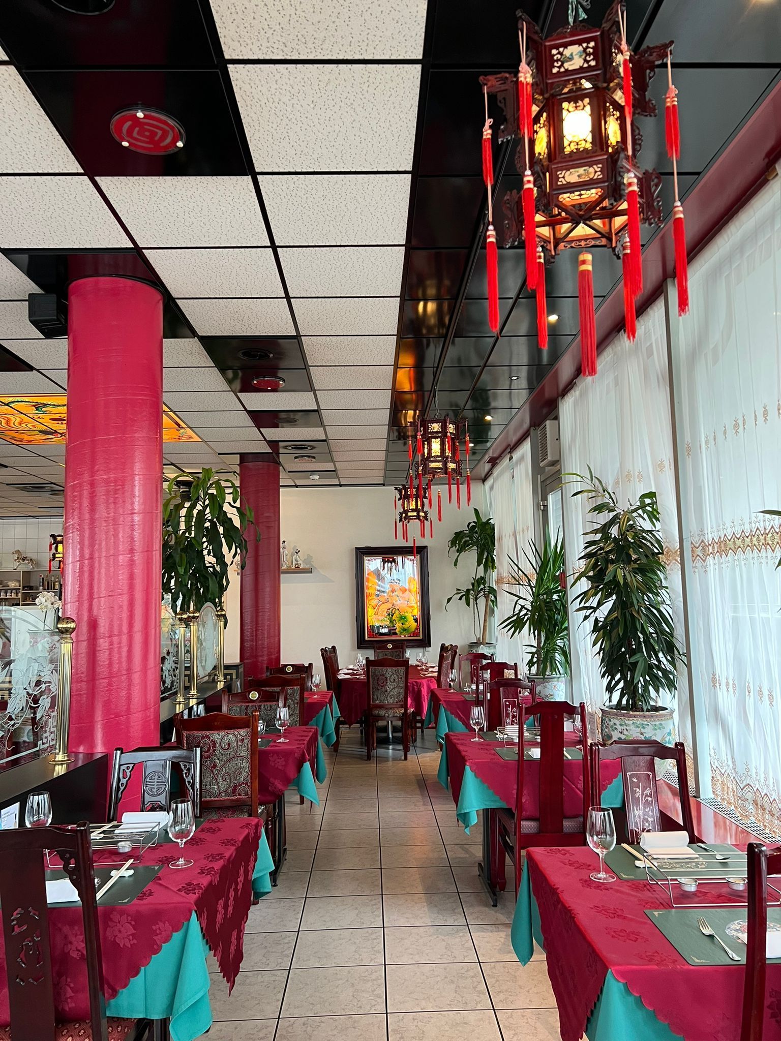 Ein langer Speisesaal mit Tischen und Stühlen und Laternen, die von der Decke hängen.