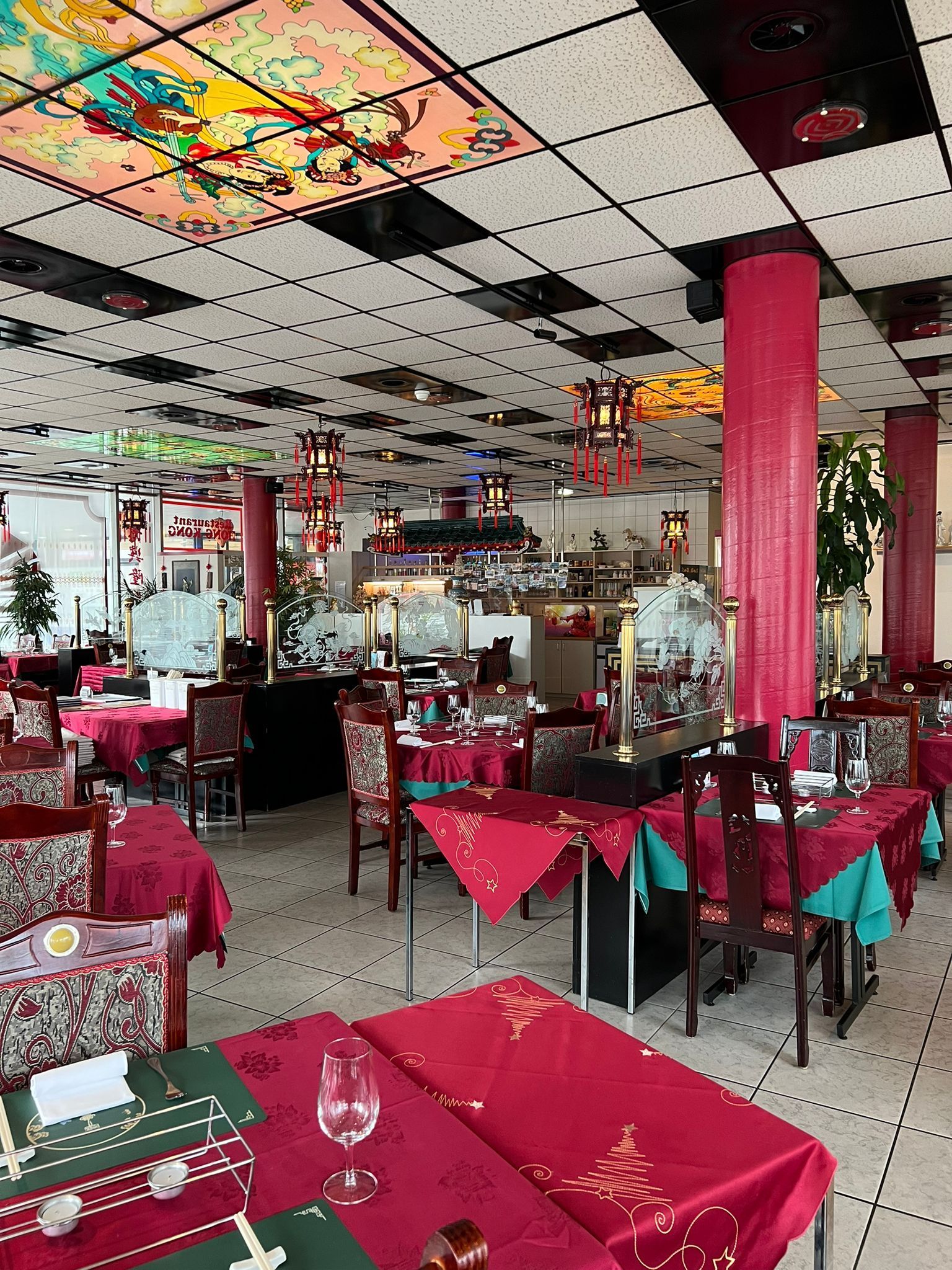 Ein großes Esszimmer mit Tischen und Stühlen und einer Buntglasdecke.