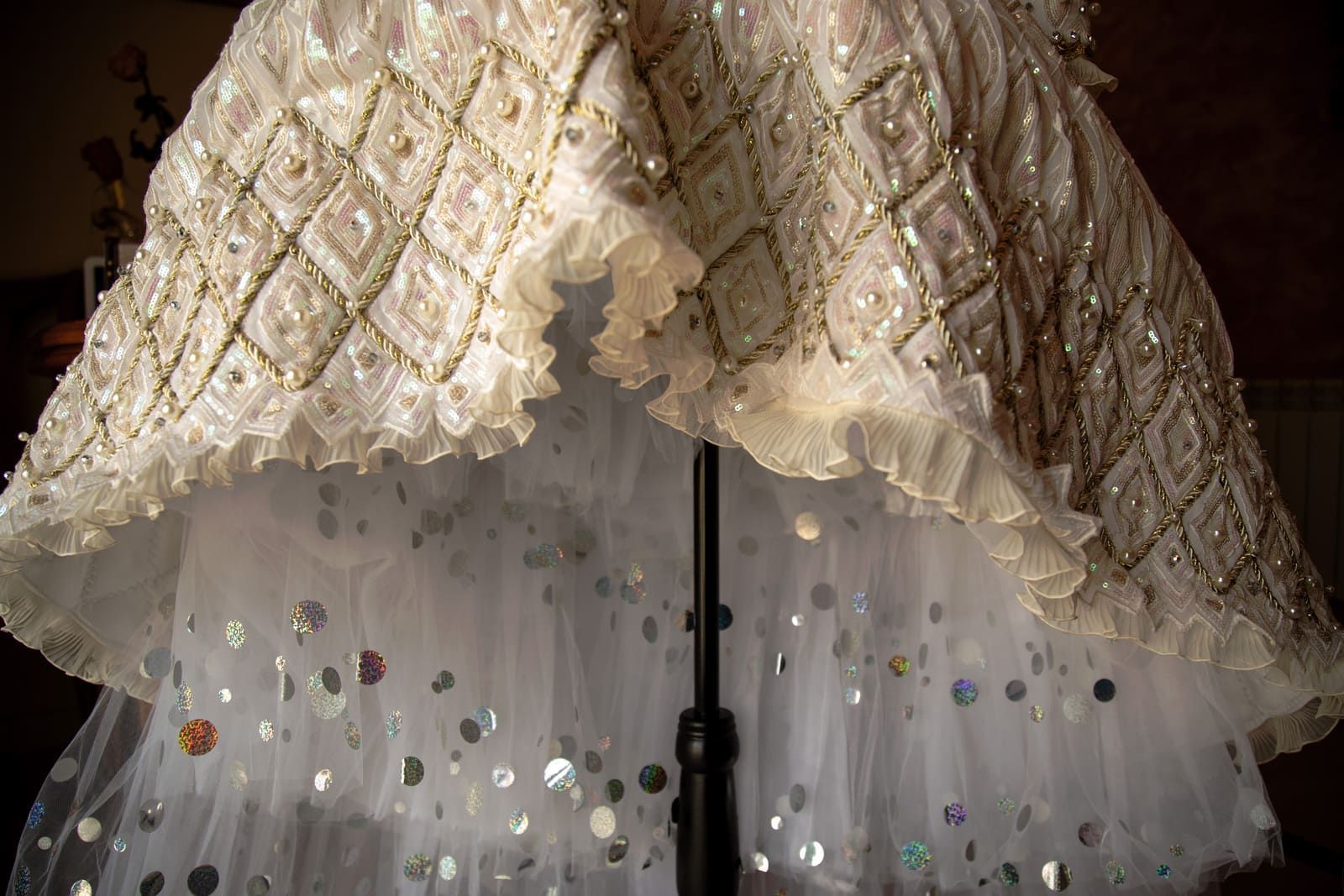 Vestido de cuentas blancas sobre maniquí, con tul con lentejuelas y bordes con volantes.