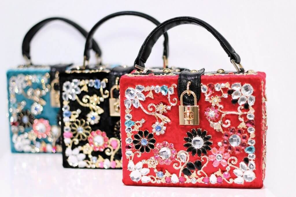 Tres bolsos están alineados uno al lado del otro sobre una superficie blanca.