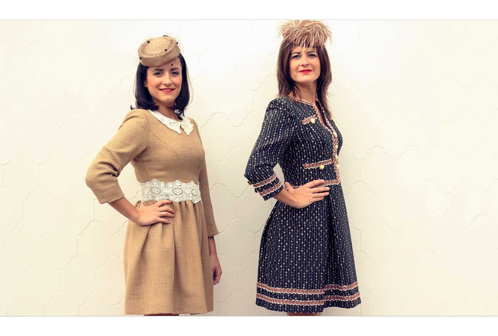 Dos mujeres están paradas una al lado de la otra, vistiendo vestidos y sombreros.