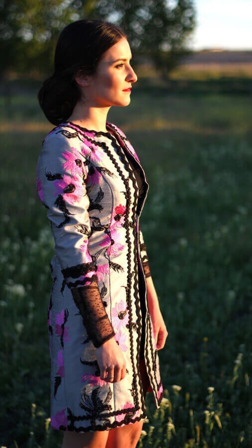 Una mujer con un vestido floral está parada en un campo.