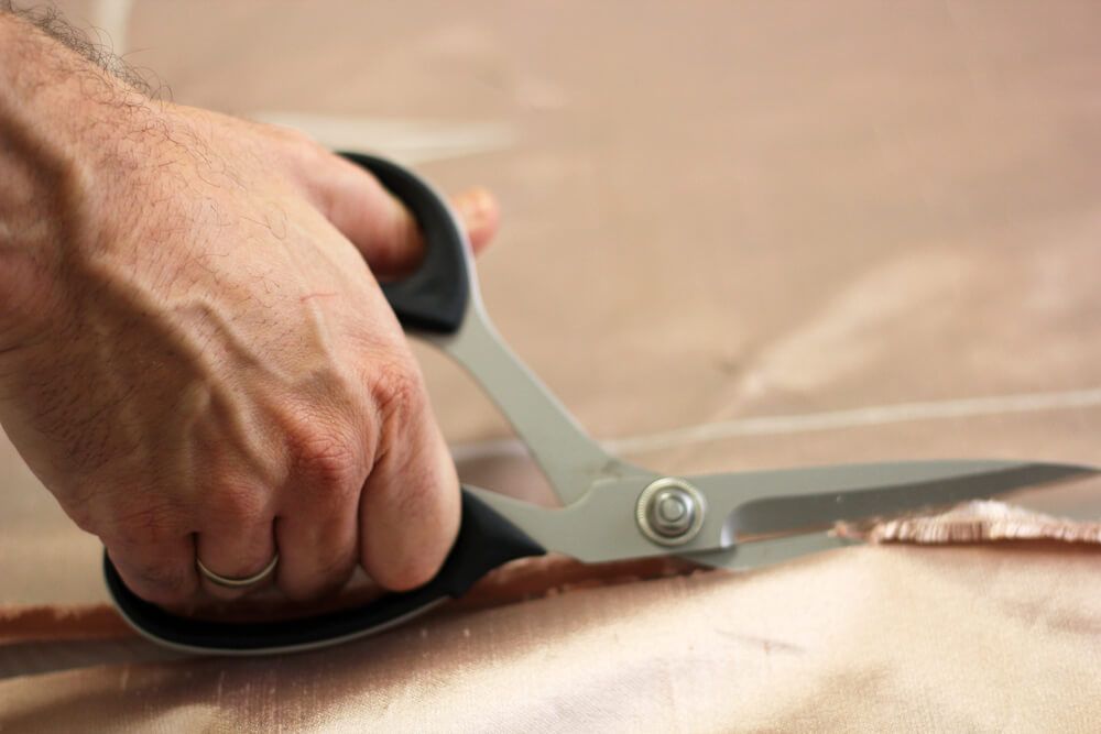 Una persona está cortando un trozo de tela con tijeras.