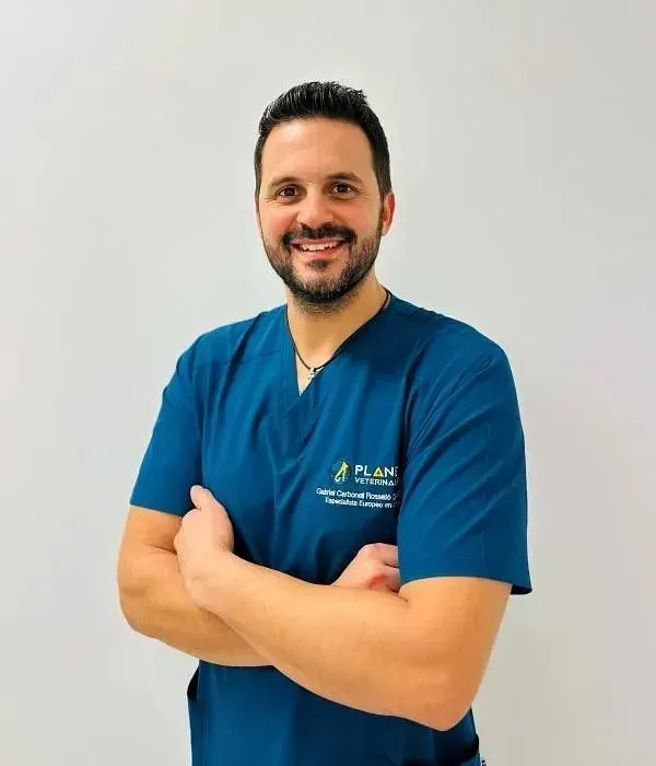 Hombre con uniforme médico azul, con los brazos cruzados y sonriendo. El logo de la camiseta dice 