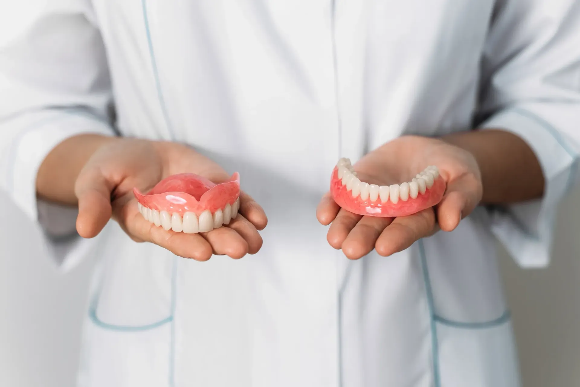 Un dentista sostiene dos dentaduras postizas en sus manos.