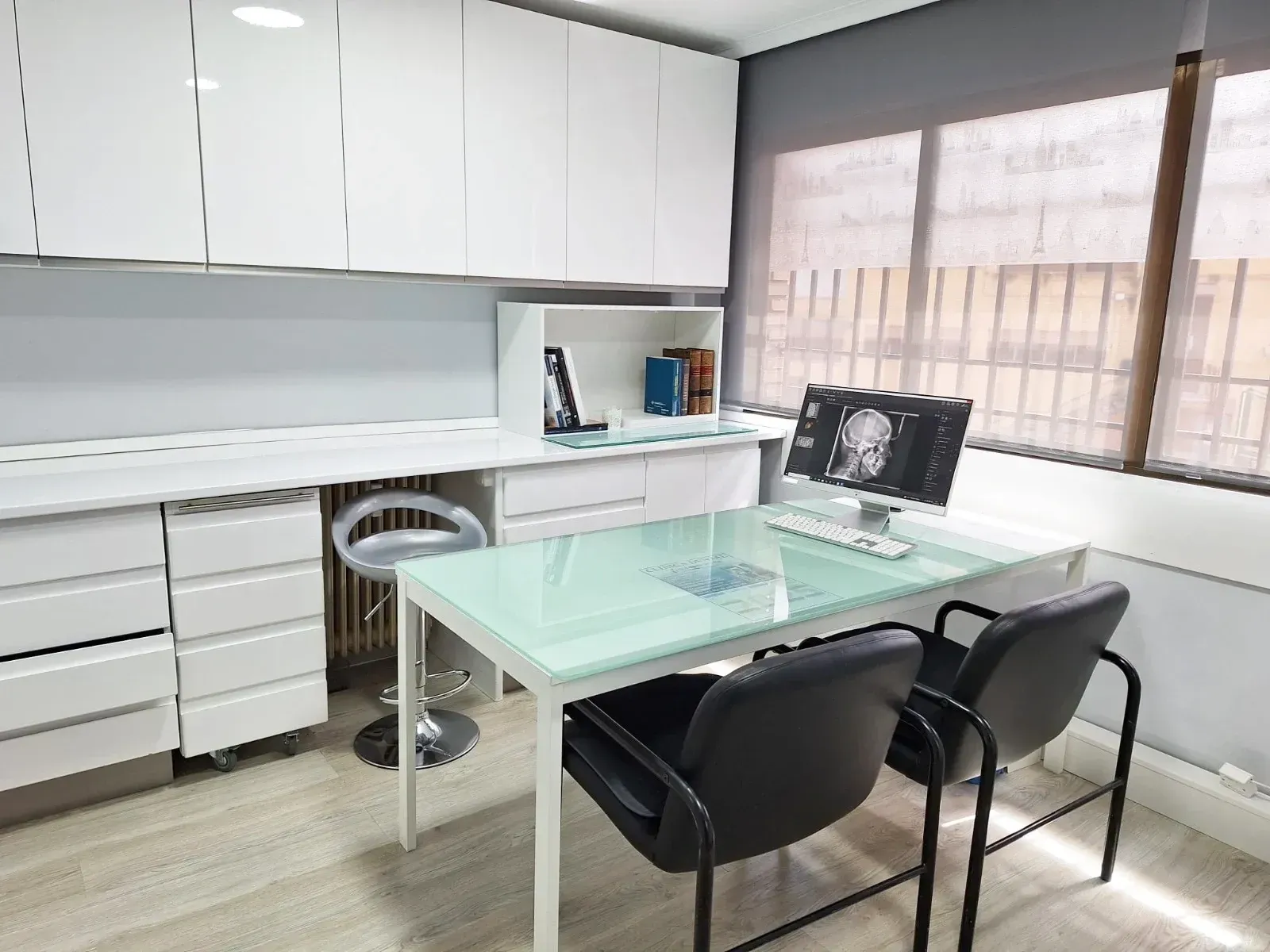 Una habitación con una mesa y sillas y una computadora encima.