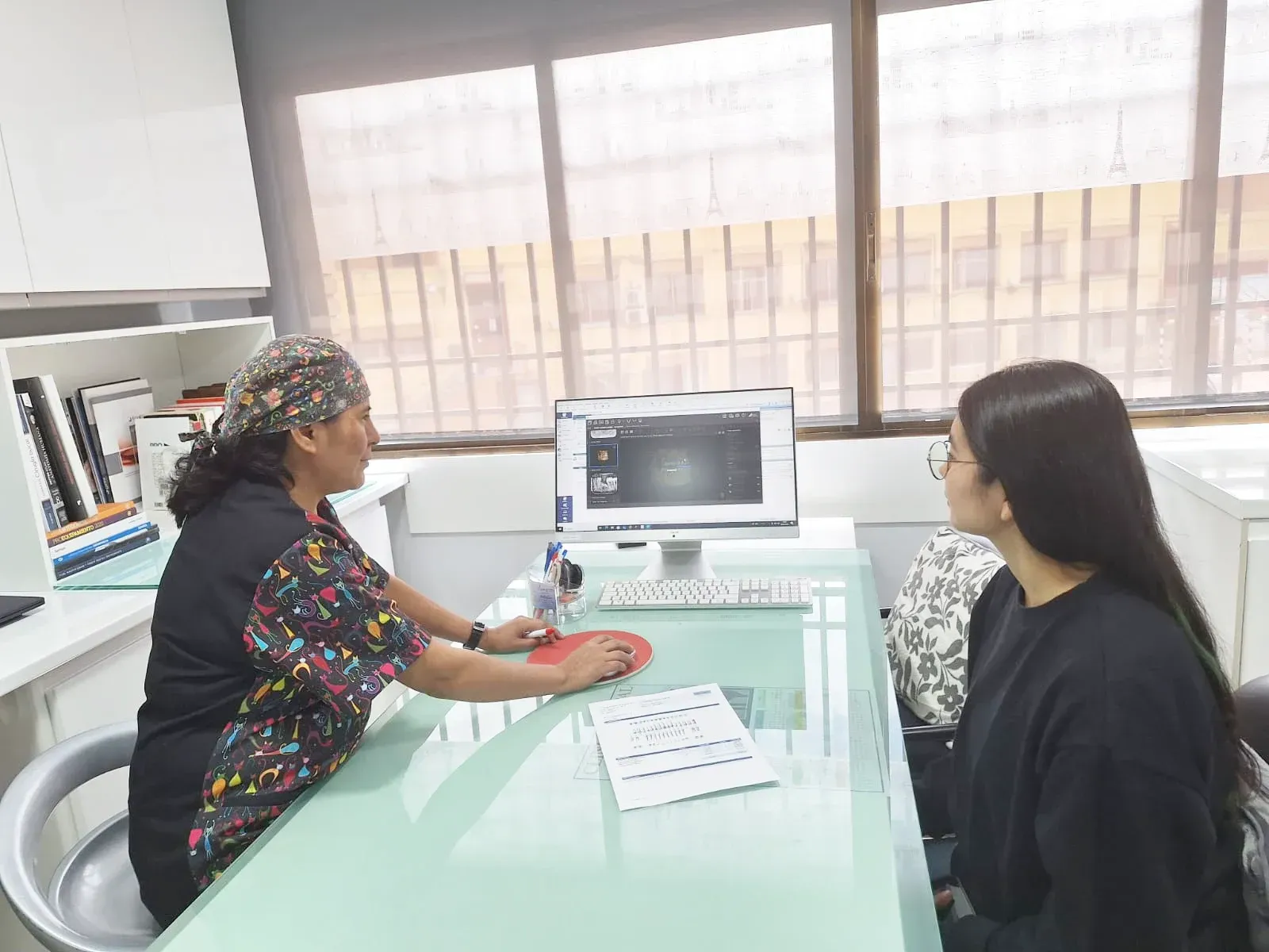 Una mujer está sentada en una mesa hablando con un médico.
