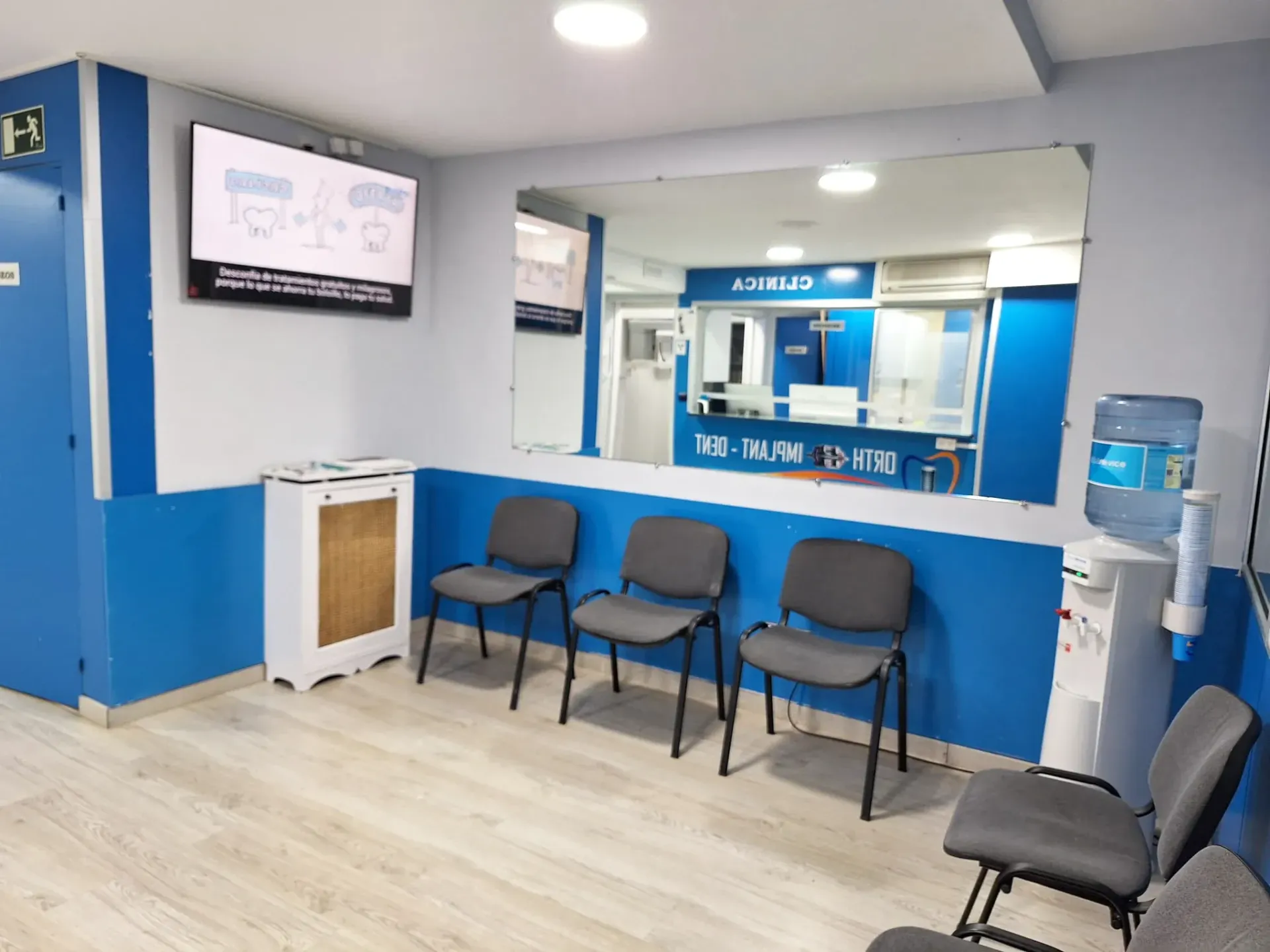 Una sala de espera con sillas y un dispensador de agua.