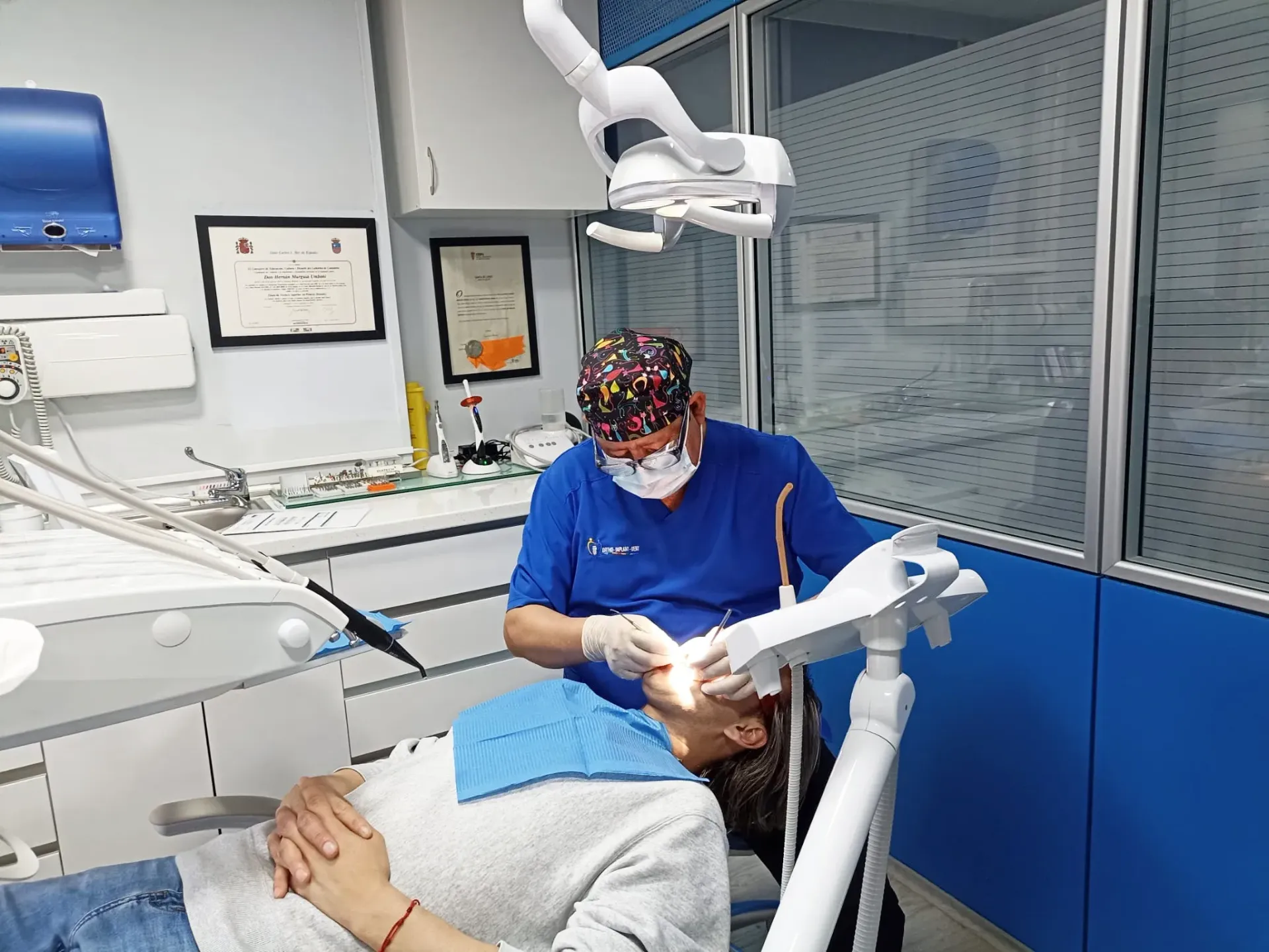 Una mujer mayor está sentada en un sofá con gafas y sonriendo.