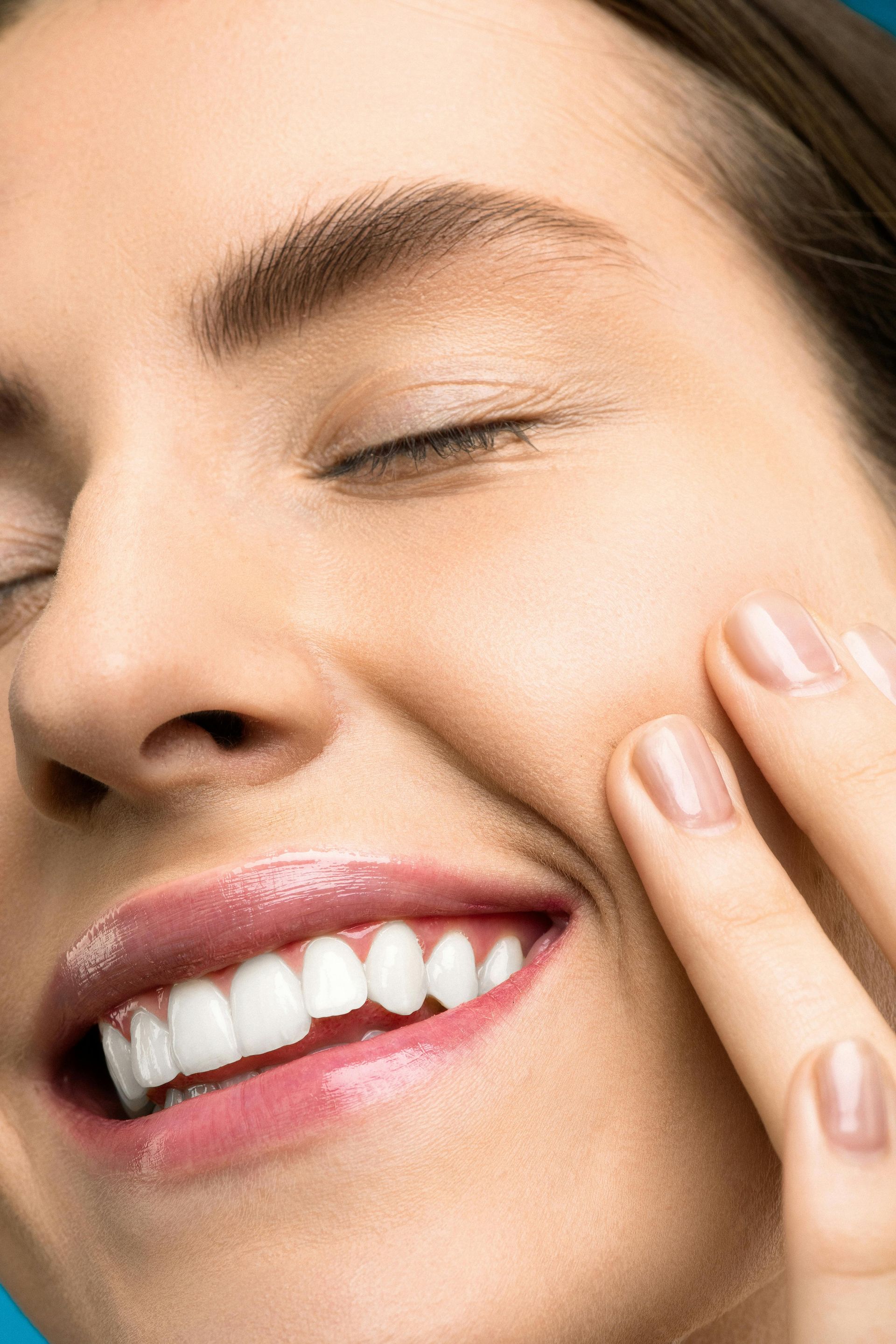 Un primer plano del rostro de una mujer con los ojos cerrados y la mano sobre la cara.