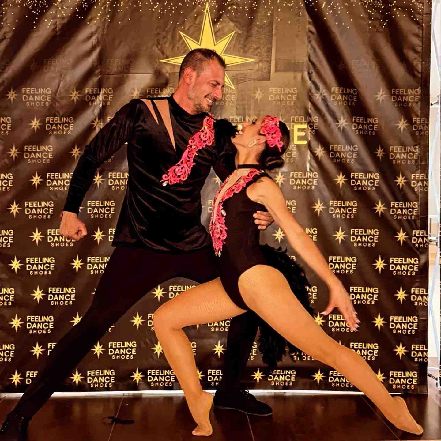 Un hombre y una mujer bailan frente a una pared que dice