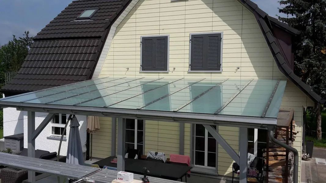 Ein großes weißes Haus mit einem Glasdach und einer Veranda.