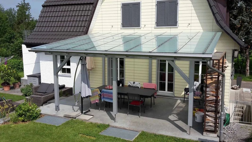 Ein grosses weisses Haus mit einer Pergola mit Glasdach. Foto von der Mannhart Holzbau AG