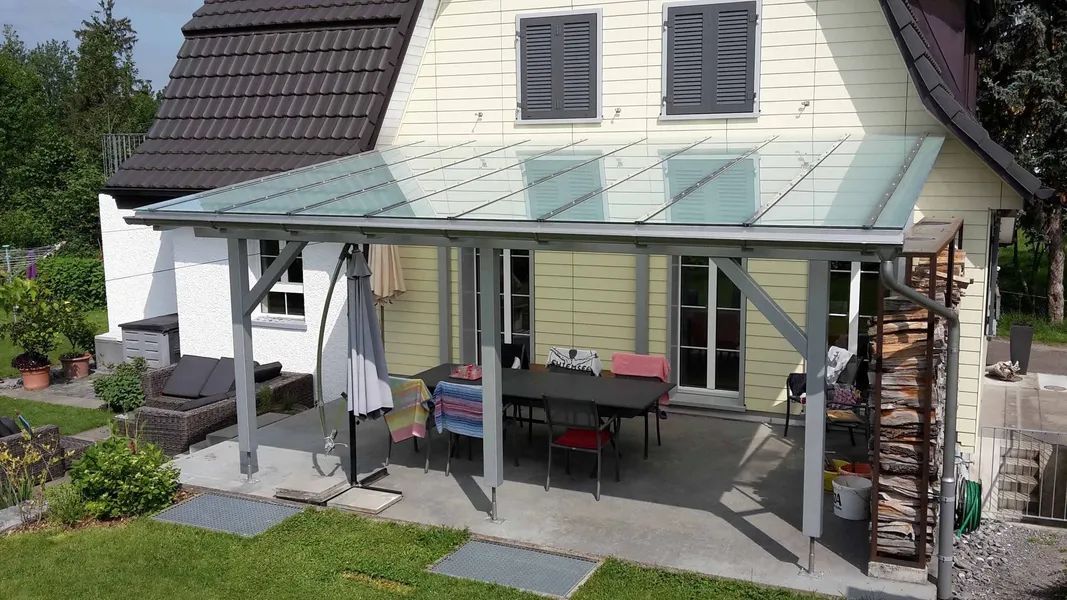 Ein grosses weisses Haus mit einer Pergola mit Glasdach. Foto von der Mannhart Holzbau AG