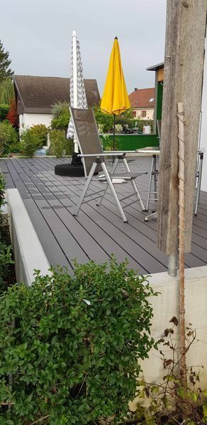 Eine Holzterrasse mit Stühlen und Sonnenschirmen.