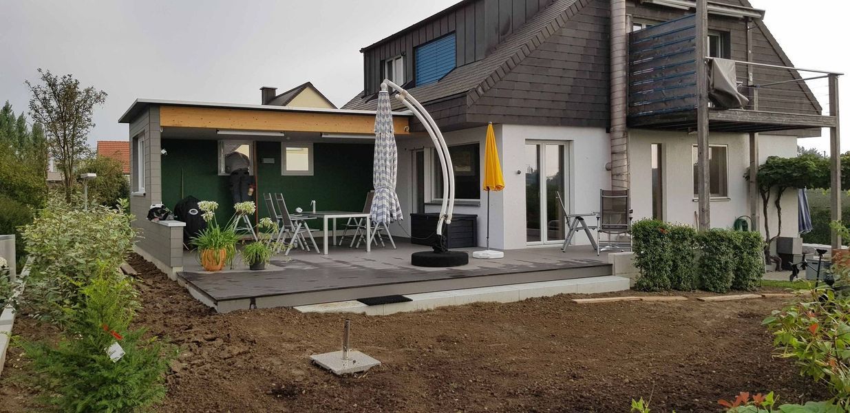 Ein Haus mit Terrasse und Sonnenschirm davor. Foto von der Mannhart Holzbau AG