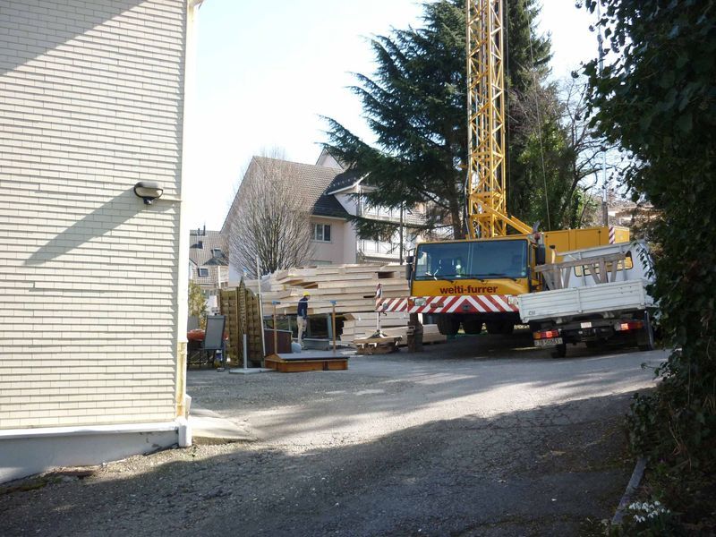 Ein weisser Lkw mit einem gelben Kran darauf. Foto von der Mannhart Holzbau AG